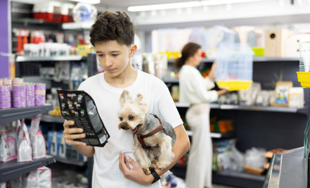 Teenager with Yorkshire terrier choosing dry dog food in pet store