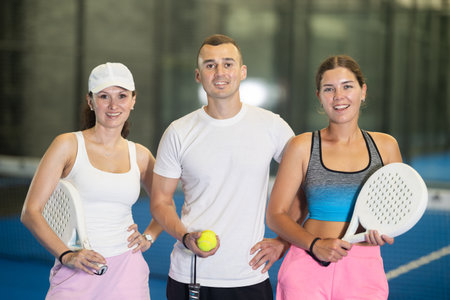 Two women and man posing on tennis courtの写真素材