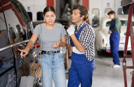 Male mechanic consulting female client on car doorの写真素材