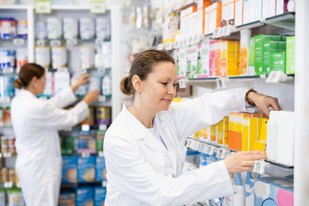 Pharmacy employee puts new healing body cosmetics on shelvesの写真素材