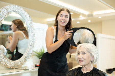 Elderly woman approving result of hairdresser work, looking satisfied with new hairdoの写真素材