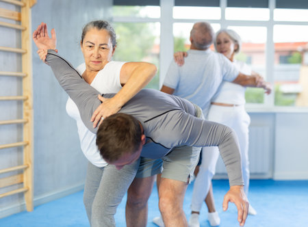 Senior woman in pair with middle-aged coach train Krav Maga and self-defense skills.の写真素材