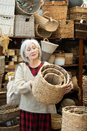 Senior woman looks at wicker basket in store.の写真素材