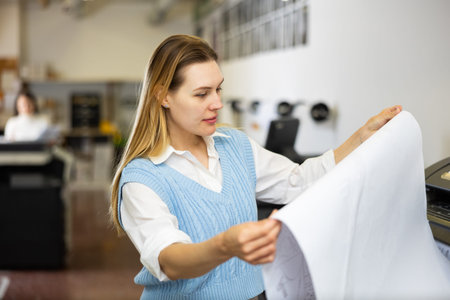 Woman checking large format paper after printing