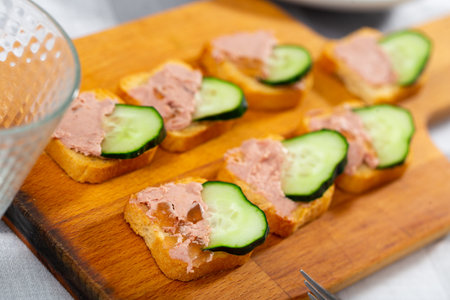 There are sandwiches with pate and cucumber on boardの写真素材