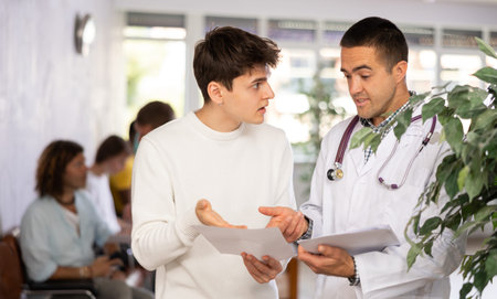 Young male doctor and patient discussing medical document