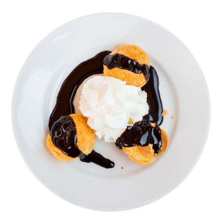 There is dessert on plate - several profiteroles, and whipped cream decorated in form of small...