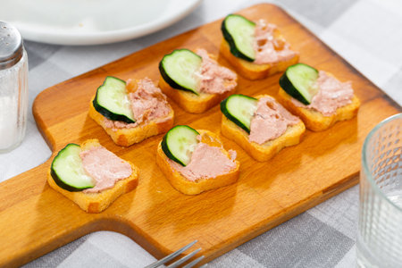 There are sandwiches with pate and cucumber on boardの写真素材
