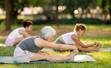 Senior woman performing yoga asanas in summer parkの写真素材