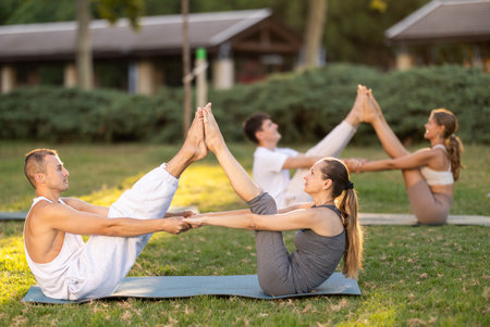 Young couple performing partner Navasana during yoga in parkの写真素材