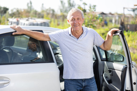European mature man has arrived in village, comes out of car