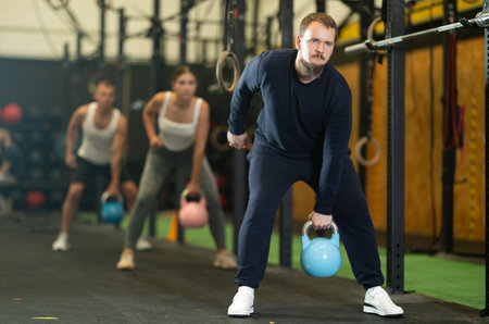 Bearded guy performing one arm kettlebell swings in gymの写真素材