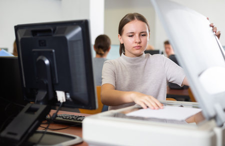 Focused female student using PC and xerox while studying computer science in the classroomの写真素材