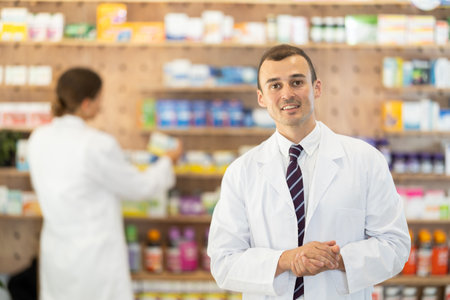 At pharmacy, man apothecary waiting for customers, invite with gesture go to department of cosmeticの写真素材