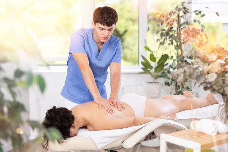 Young guy doing a back massage to adult womanの写真素材