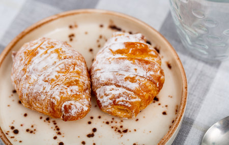 Stuffed croissants covered with powdered sugar for breakfastの写真素材