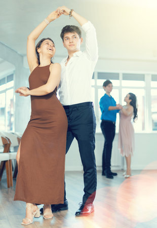 Hispanic guy enjoying merengue with female partner in dance class