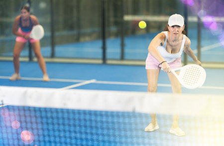 Young and adult women playing doubles tennisの写真素材