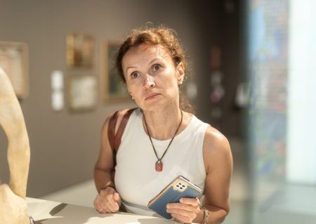 Woman with phone looking at museum exhibit