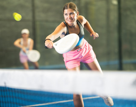 Young and adult women playing doubles tennisの写真素材