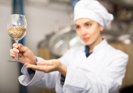 Female brewmaster holding glass of maltの写真素材