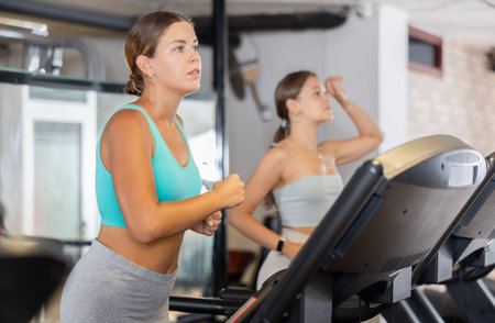 Focused motivated girl leading healthy active lifestyle doing cardio workout in gym, running on...