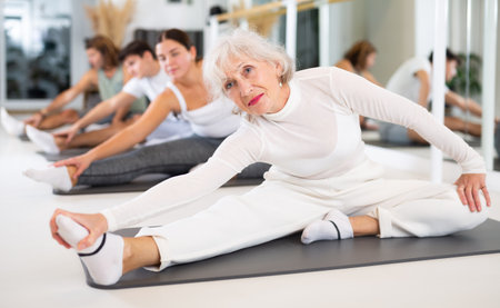 Ðctive senior woman performs exercises on a pilates mat in the hall of a modern fitness studio.の写真素材