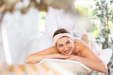 Young woman relaxing in spa center during back and shoulders massageの写真素材