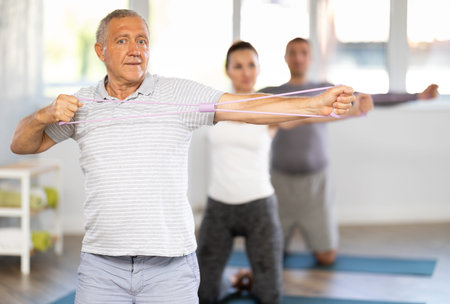 Elderly man exercising with pilates loop