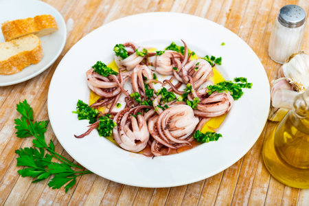Delicious spanish dish baby octopuses or tentacles on plate with herbs