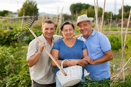 Happy elderly parents and adult son enjoying favorite pastime in garden