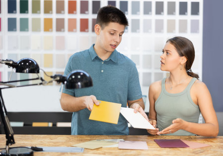 Man and woman picking paint samples. Couple choosing color in household storeの写真素材