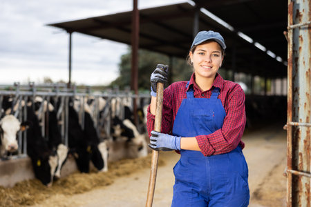 Young female farmer posing while feeding cows at farmの写真素材
