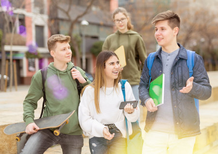 Company of teenagers are communicating on walk on streetの写真素材