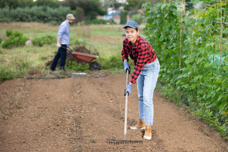 Peasant girl is working in garden with rakeの写真素材