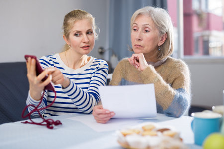 Mature woman and her adult daughter study an important document