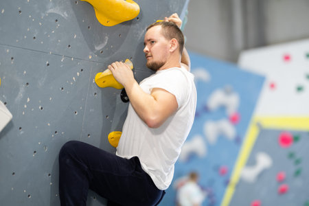 Young man practicing rock climbing on climbing wall