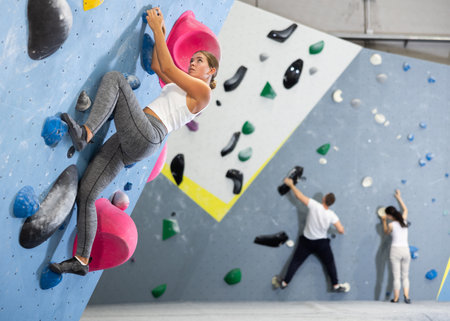 Sportive woman climbing on artificial rock wall in rock climbing gymの写真素材