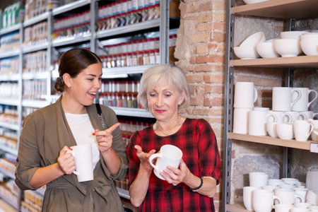Elderly woman and young woman choose pottery clay cupの写真素材