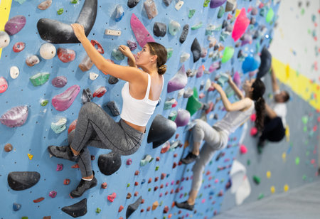 Sportive woman climbing on artificial rock wall in rock climbing gymの写真素材