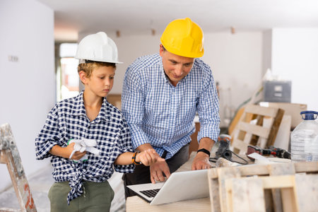 Young boy and his father discussing work plan in new apartment