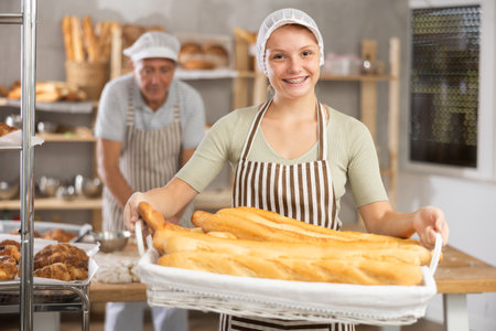 Bakery girl employee holds ready-made baguettes.の写真素材