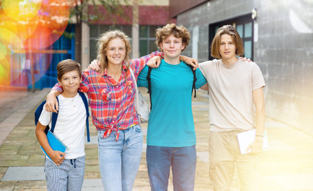 Group of positive cheerful teenagers hanging out on streets of city on day