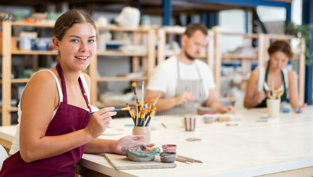 Three craftsperson are busy painting clay productsの写真素材