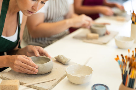 Close up girl forms bowl of clay during master class, top view