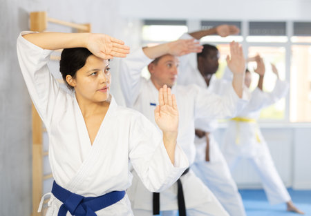 Middle-aged woman attendee of karate classes practicing kata standing in row with othersの写真素材