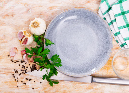 On table there are several cloves of garlic, parsley next to white plateの写真素材