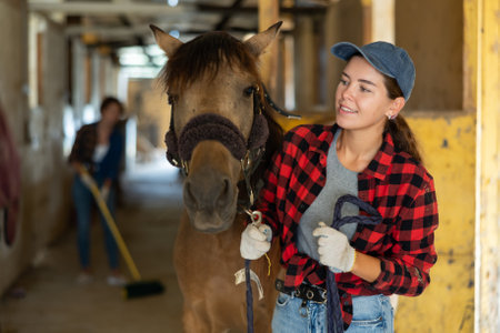 Portrait of smiling woman horse farm worker standing at stableの写真素材