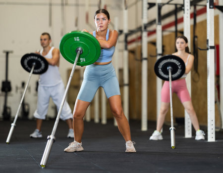 Athletic young woman doing barbell exercises in crossfit gymの写真素材