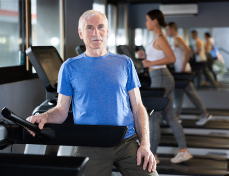 Portrait of elderly man running on treadmill in sport gymの写真素材